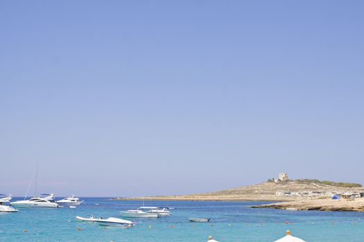 Coastline in Malta with blue sea, blue sky and power boats. Space for text