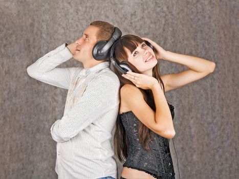 A girl and a boy, smiling happily, listening to music via headphones