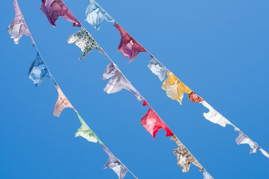 A group of colored shirts on a clothesline in front of blue sky