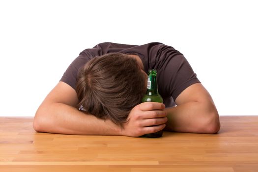 Drunk man sleeping on a wooden table with a bottle of beer. Isolated on a white background