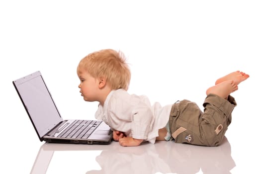 Young boy looking at a laptop on a stool. Isolated on white background