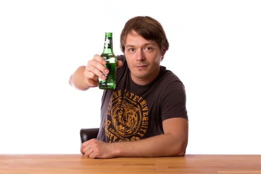 Man sitting at a wooden table with a bottle of beer.  Isolated on a white background