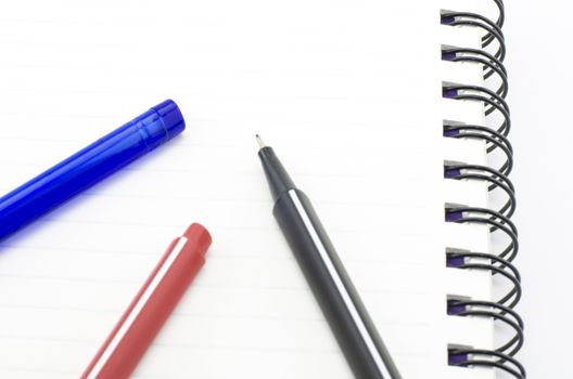 black red and blue pen with notebook isolated on white background