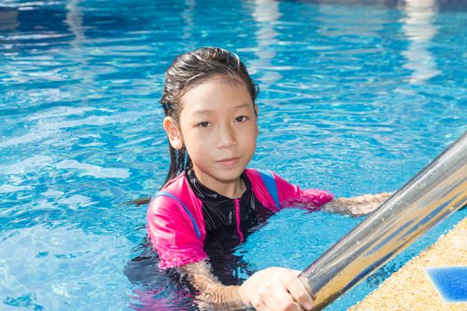 Girl relaxing on the side of a swimming pool