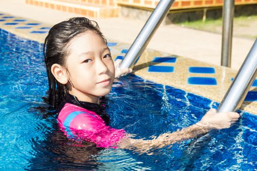 Girl relaxing on the side of a swimming pool