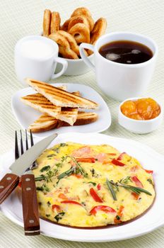 Arrangement of Delicious Omelet with Vegetables, Toasts, Apricot Jam, Cup of Coffee, Milk and Puff Pastry closeup on light green Checkered background