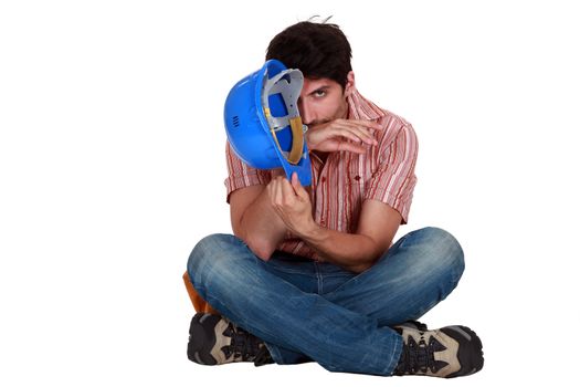 A male construction worker sitting on the floor.