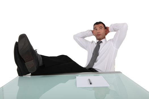 young businessman having a break with legs on table and arms behind head