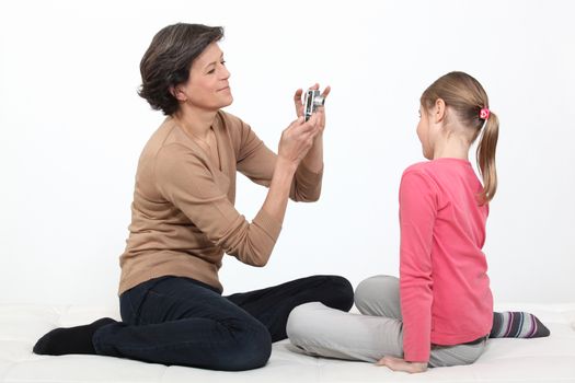 mother taking picture of young daughter isolated on white