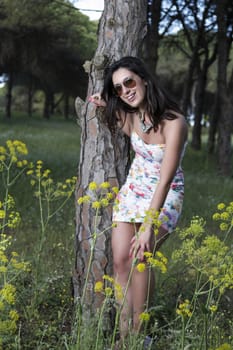 View of a young woman in a floral tight and short dress posing in nature.