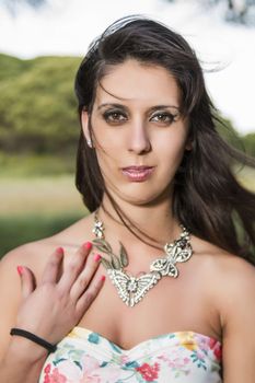 View of a young woman in a floral tight and short dress posing in nature.