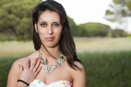 View of a young woman in a floral tight and short dress posing in nature.