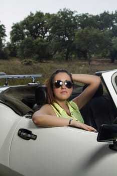 View of a beautiful woman posing on a white convertible car.