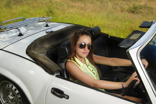 View of a beautiful woman posing on a white convertible car.