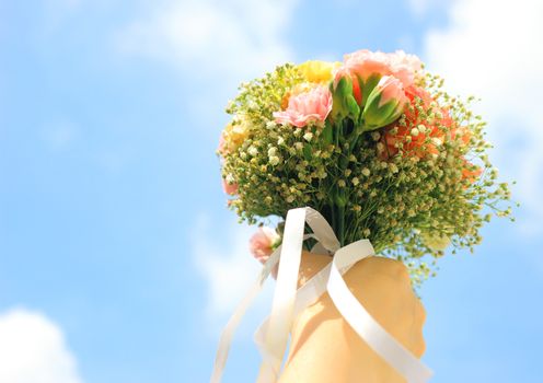 Bouquet of flower in hand and blue sky 