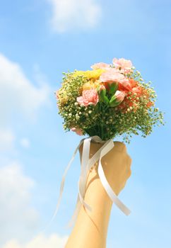 Bouquet of flower in hand and blue sky 