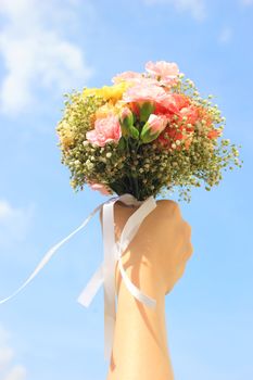 Bouquet of flower in hand and blue sky 
