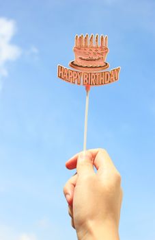 Hand holding happy birthday tag with blue sky