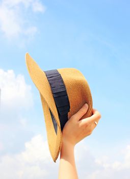 Woman hand holding panama hat with blue sky