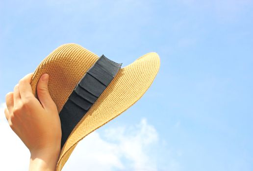 Woman hand holding panama hat with blue sky