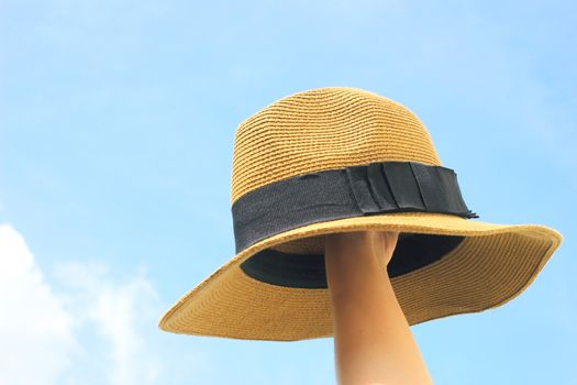 Woman hand holding panama hat with blue sky