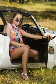 View of a beautiful woman posing on a white convertible car.