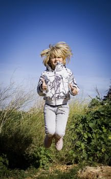 A child jumping outside thumbs up