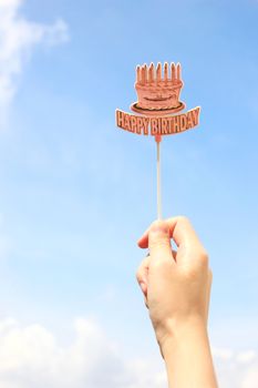 Hand holding happy birthday tag with blue sky