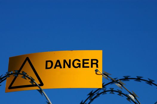 A danger sign on some razor wire, with blank space for extra text