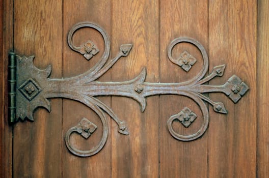 Close-up Of An Ornamental Iron Hinge On An Old Wooden Door