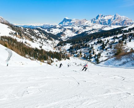 Skiers going down the slope at Sella Ronda ski route in Italy