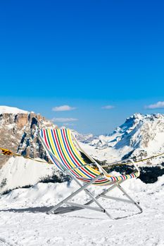 Empty folding chair on top of a mountain against ski area