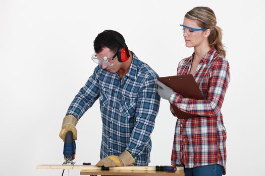 Man using band saw whilst woman supervises
