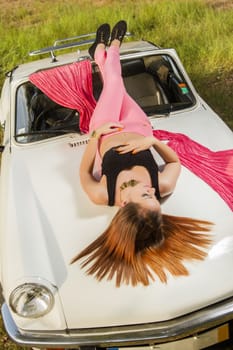 View of a beautiful woman posing on a white convertible car.