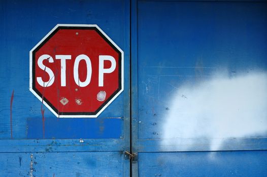 A Red Stop Sign on a Locked Blue Door of an Abandoned Warehouse with Copy Space