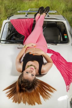 View of a beautiful woman posing on a white convertible car.