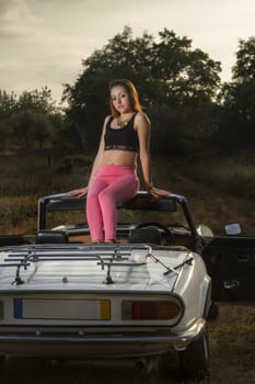 View of a beautiful woman posing on a white convertible car.