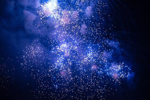 Sparks of a fireworks against dark night sky - class of explosive pyrotechnic devices used for aesthetic and entertainment purposes