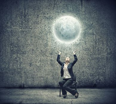 image of businesswoman holding moon in hands above head