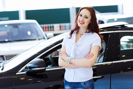 Pretty woman standing near car at car center. Choosing a car