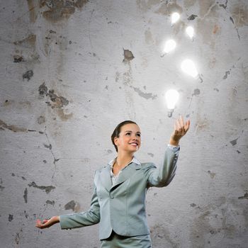 Image of attractive smiling businesswoman holding light bulbs on hand