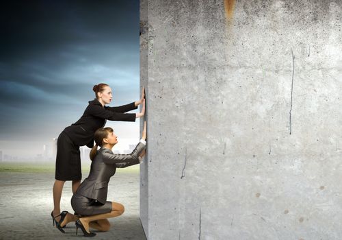 Two businesswoman pushing blank wall. Place for text