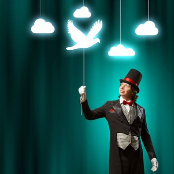 Image of man magician showing trick against color background