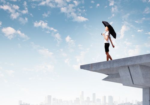 Image of businesswoman standing at the edge of bridge. Risk concept