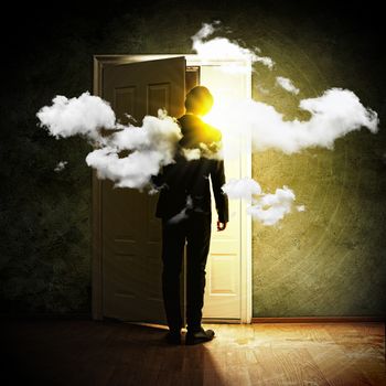 Image of young businessman standing with back opening door