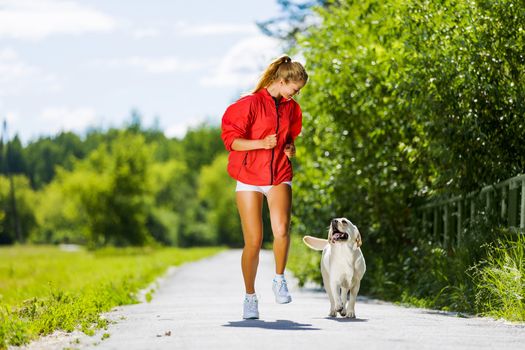 Young attractive sport girl running with dog in park