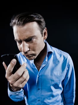 one caucasian man angry looking at telephone videophone smartphone  portrait isolated studio on black background