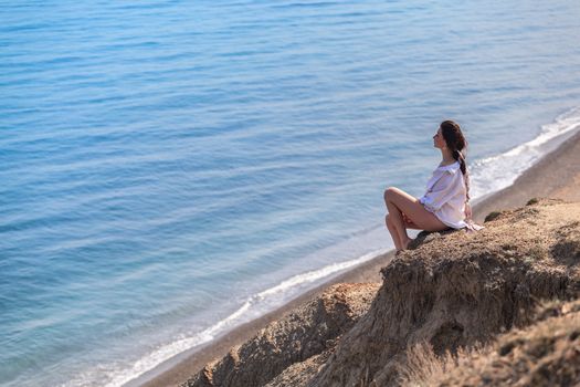 Girl sitting on a rock and looking at sea