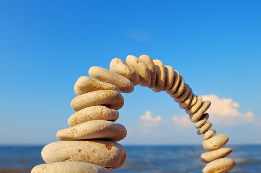 Balancing of white pebbles on sky background