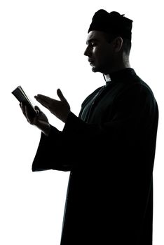 one caucasian man priest reading bible silhouette in studio isolated on white background
